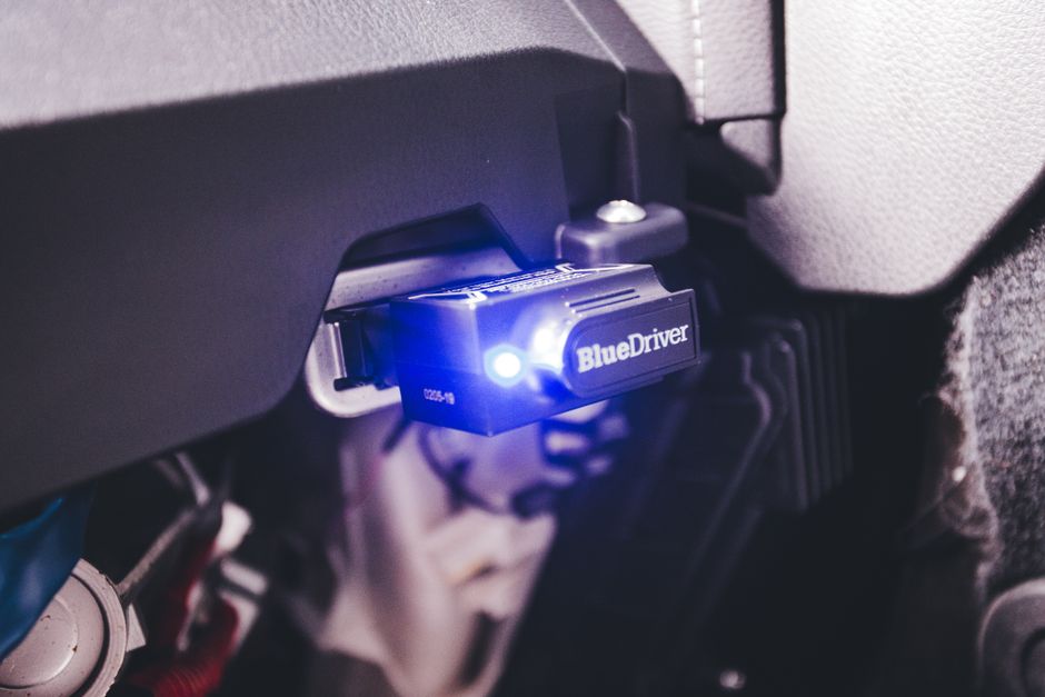 Close-up of a BlueDriver electronic car diagnostic tool plugged in a vehicle.